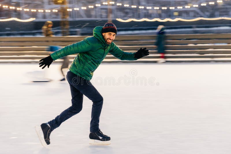 Disparado do homem alegre tem o divertimento exterior, patins no anel do gelo, apreciam imagens de stock Disparado do homem alegre tem o divertimento exterior, patins no anel do gelo, apreciam imagens de stock