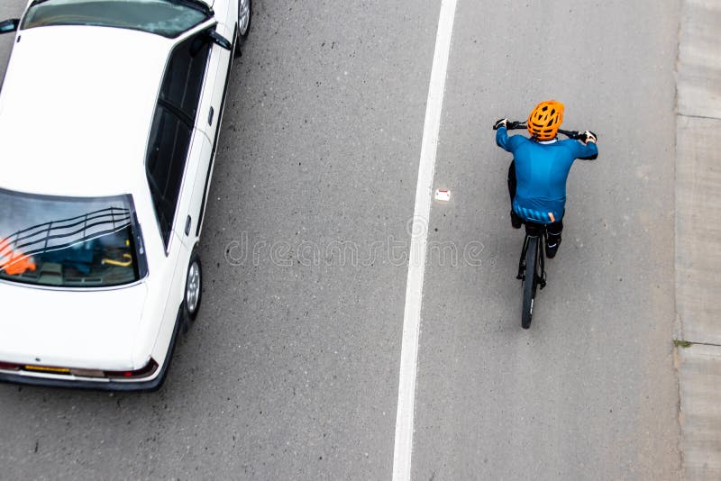 Overhead shot of  a cyclist being overtaken by a car on the road between Bogota and La Calera on the mountains in Colombia. Overhead shot of  a cyclist being overtaken by a car on the road between Bogota and La Calera on the mountains in Colombia