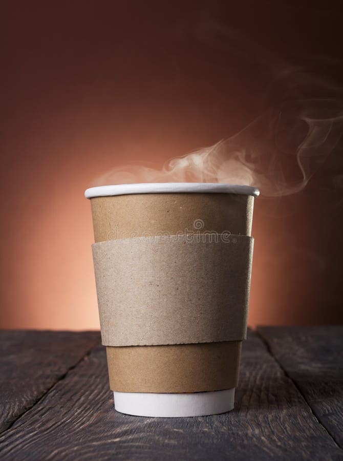 Disposable Cup of steaming hot coffee on wooden table