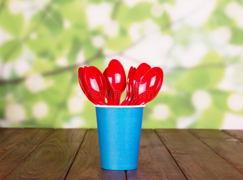 Disposable Cups and Plastic Spoons on Abstract Green Background. Stock