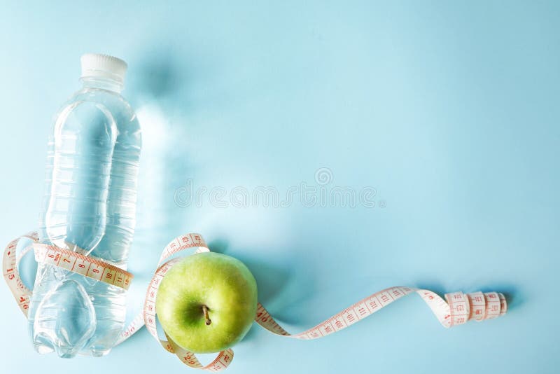 Disposizione piana di dieta un nastro del tester e mela verde e una bottiglia di acqua Fondo blu con lo spazio della copia concet immagine stock Disposizione piana di dieta un nastro del tester e mela verde e una bottiglia di acqua Fondo blu con lo spazio della copia concet immagine stock