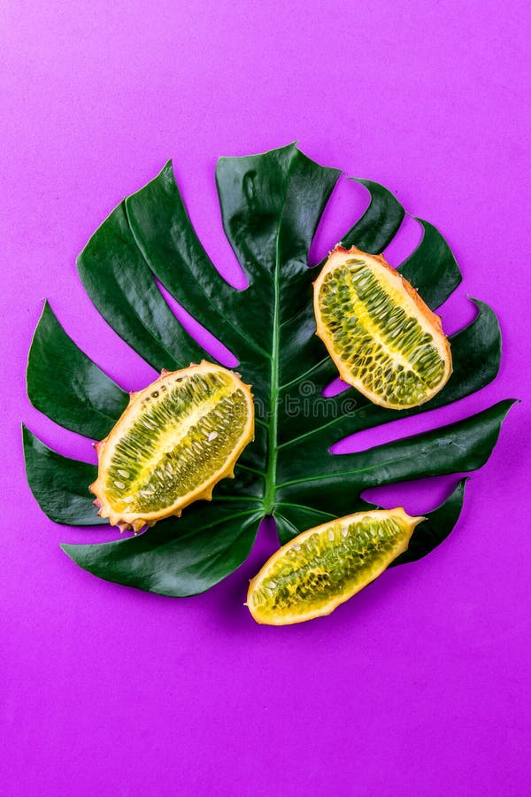 Disposição criativa feita de frutos tropicais do verão e do monstera tropical das folhas no fundo roxo Configuração lisa tropical fotografia de stock Disposição criativa feita de frutos tropicais do verão e do monstera tropical das folhas no fundo roxo Configuração lisa tropical fotografia de stock