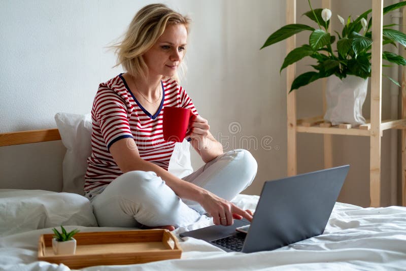 Distance learning online education and work.Happy woman girl working office work remotely from home on bed. Using