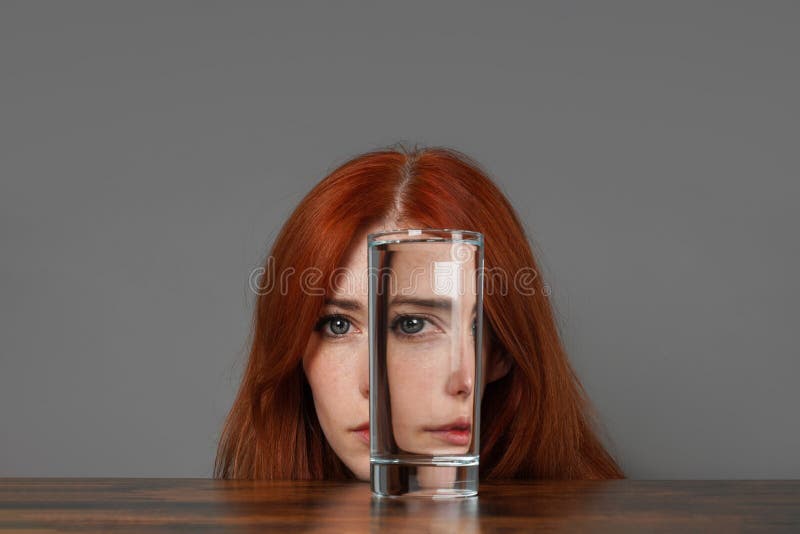 distorted face of woman looking through glass of water