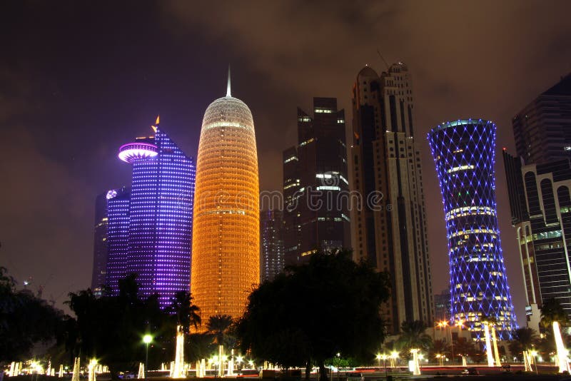 Doha business district - including landmark skyscrapers such as Burj Qatar (in orange), World Trade Center Qatar (in blue on the left) and Tornado Tower (in blue on the right) at night. Doha business district - including landmark skyscrapers such as Burj Qatar (in orange), World Trade Center Qatar (in blue on the left) and Tornado Tower (in blue on the right) at night.