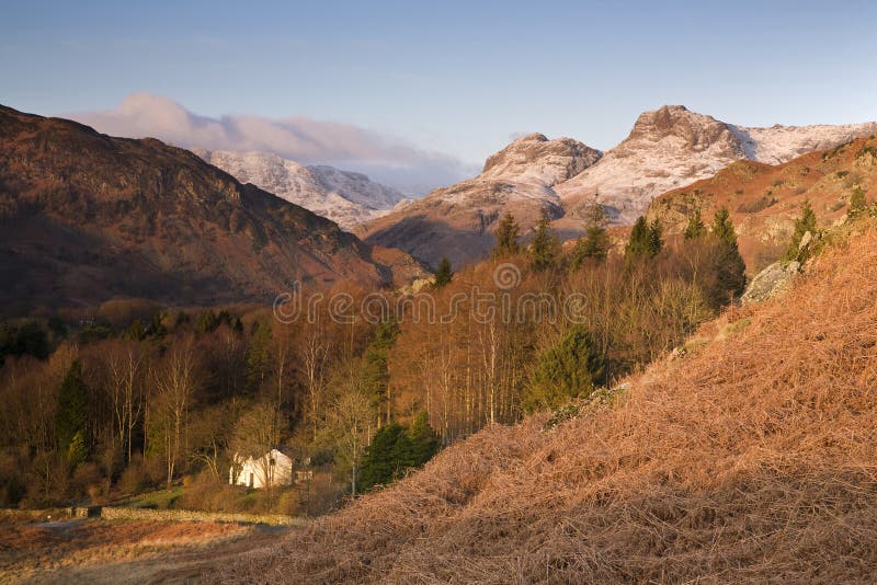 A light dusting of snow lies on top of the Langdale Pikes bathed in a warm winter sunrise in the English Lake District. A light dusting of snow lies on top of the Langdale Pikes bathed in a warm winter sunrise in the English Lake District.