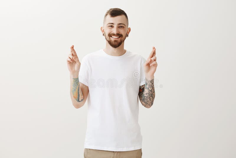 Dita dell'incrocio per fortuna Ritratto dell'uomo europeo allegro felice con i tatuaggi, desiderante o sperante per il successo d immagine stock libera da diritti