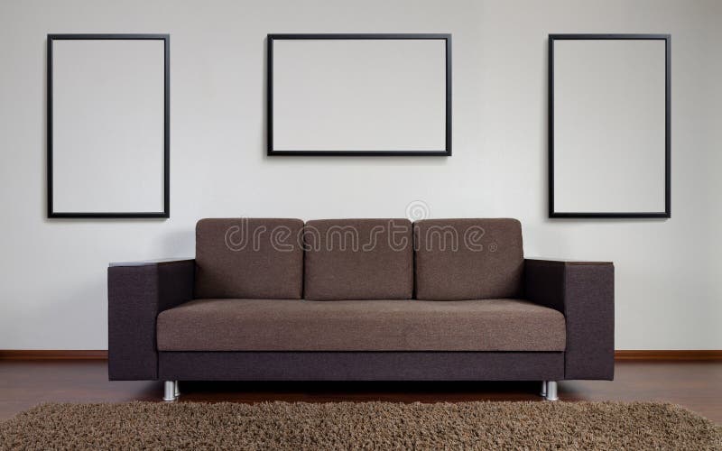 Divan moderne avec des cadres de décoration de mur photographie stock libre de droits Divan moderne avec des cadres de décoration de mur photographie stock libre de droits
