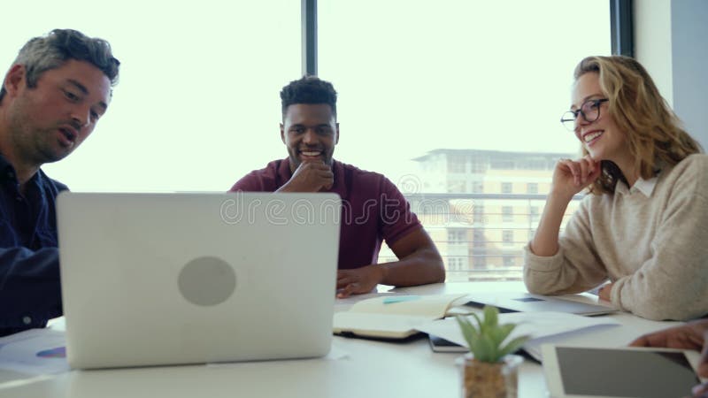 Divers team van medewerkers die samenwerken aan een samenwerkingsproject dat laptops gebruikt en papierwerk bespreekt