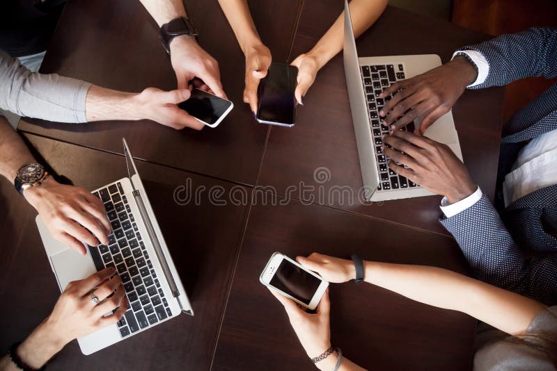 Diversa gente multirazziale che per mezzo degli smartphones dei computer portatili sulla tavola, t fotografia stock libera da diritti Diversa gente multirazziale che per mezzo degli smartphones dei computer portatili sulla tavola, t fotografia stock libera da diritti