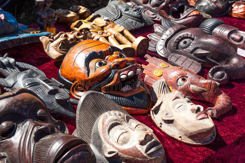 Diversas máscaras asiáticas o africanas de madera en venta en el mercado de pulgas, al aire libre fotografía de archivo libre de regalías Diversas máscaras asiáticas o africanas de madera en venta en el mercado de pulgas, al aire libre fotografía de archivo libre de regalías