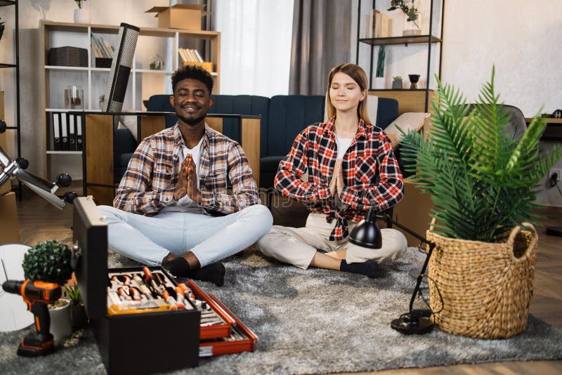 Diverse couple meditation at new flat during relocation royalty free stock images