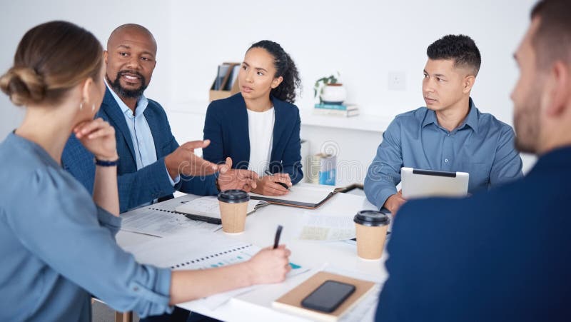 Diverse group of business people talking in a meeting and using technology and paperwork in a boardroom. Team of