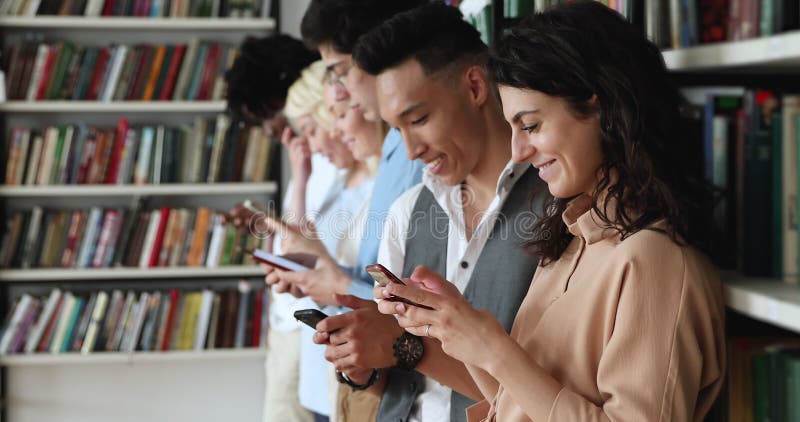 Diverse jongeren staan in de rij in de bibliotheek met telefoons