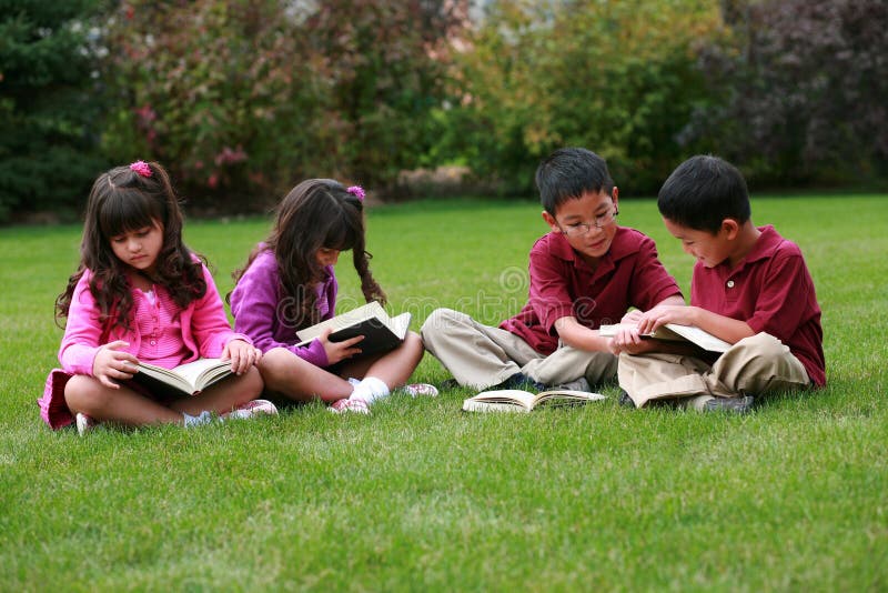 Más étnico grupo de lectura en el césped.