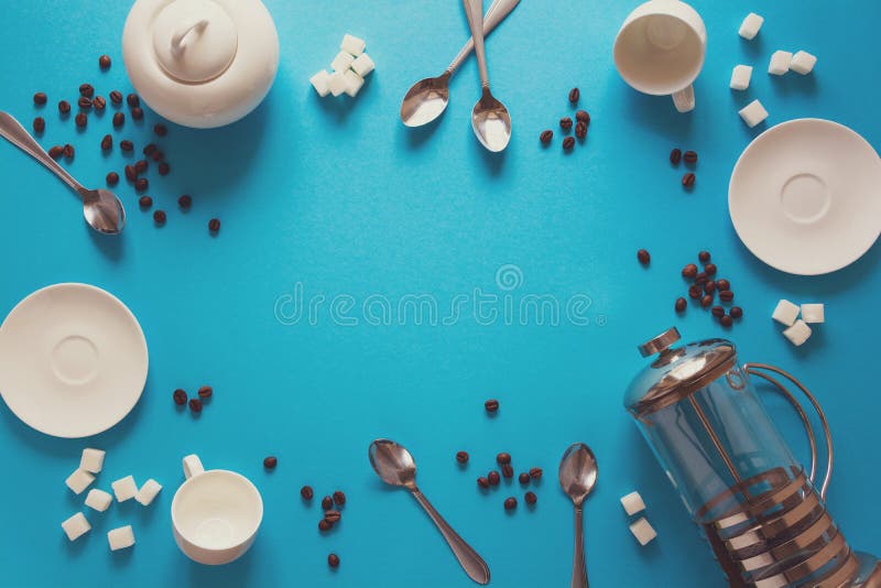 Diverse koffie die toebehoren maken: Franse koffiepers, koppen, schotels, koffiebonen, lepels en suiker op blauwe document achter stock foto Diverse koffie die toebehoren maken: Franse koffiepers, koppen, schotels, koffiebonen, lepels en suiker op blauwe document achter stock foto