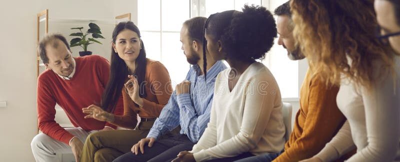 Group of diverse people sitting on row of chairs, communicating and sharing opinions