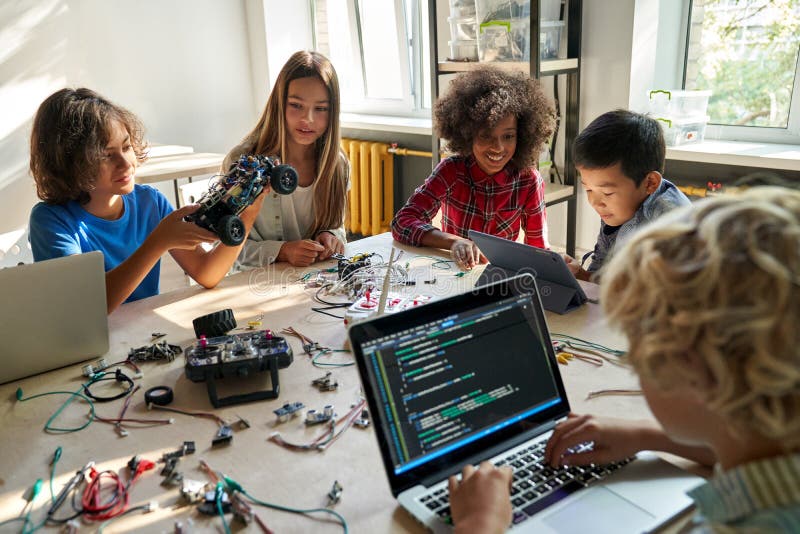 Diverse school children students build robotic cars using computers and coding. royalty free stock photos
