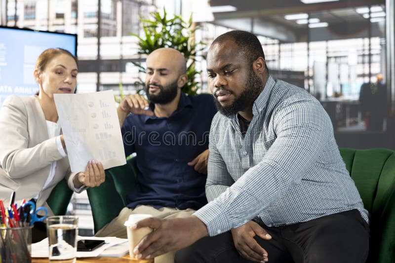 Diverse team of office clerks looking over revenue figures on documents royalty free stock photo