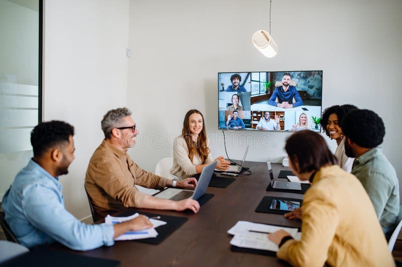 A diverse team of professionals enthusiastically participates in a video conference call stock image