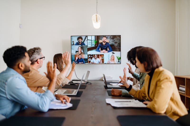 A diverse team of professionals enthusiastically participates in a video conference call stock image