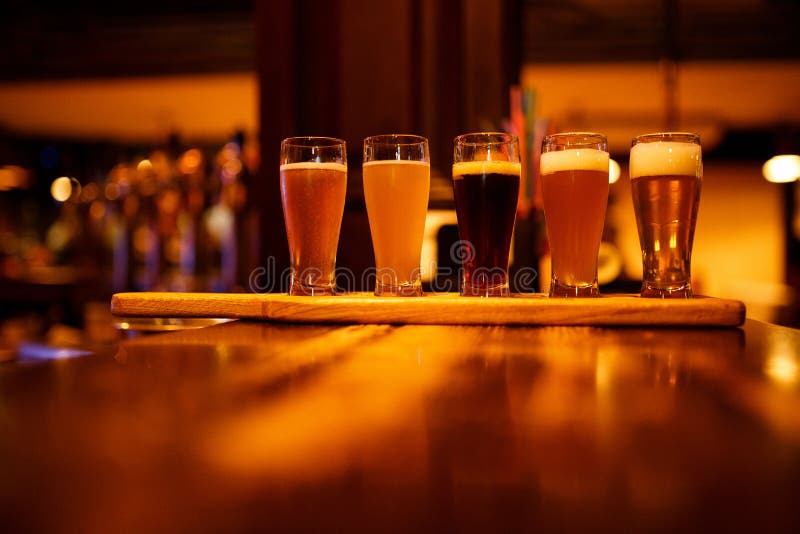 Diverse types van ambachtbier in kleine glazen op een houten lijst in een bar