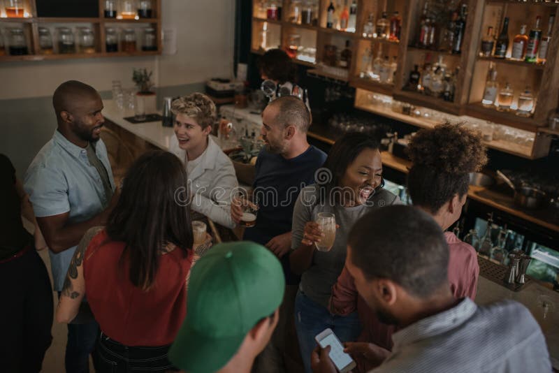 Diverse young friends talking over drinks in a bar stock photo Diverse young friends talking over drinks in a bar stock photo