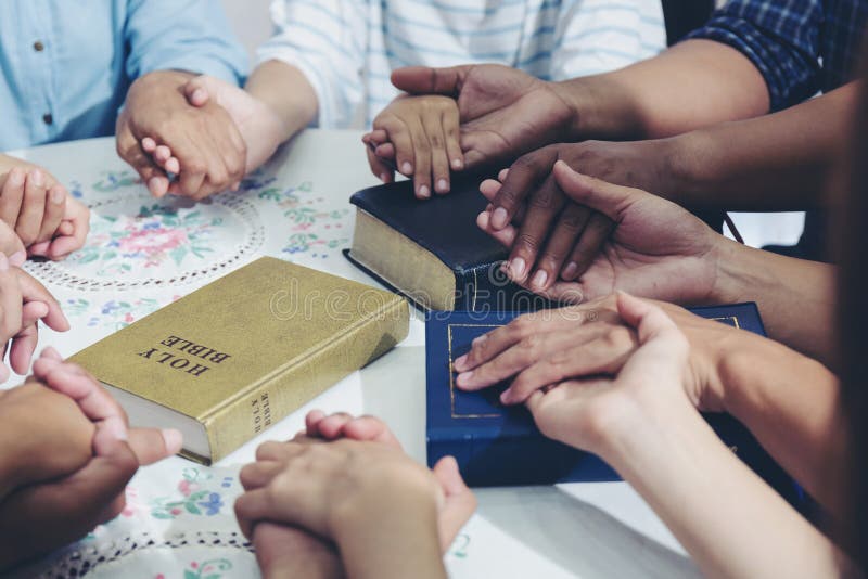 Diverses mains tendues serrent la main pour prier pour Dieu l'un l'autre soutiennent ensemble le travail d'équipe avec la bible s photographie stock libre de droits