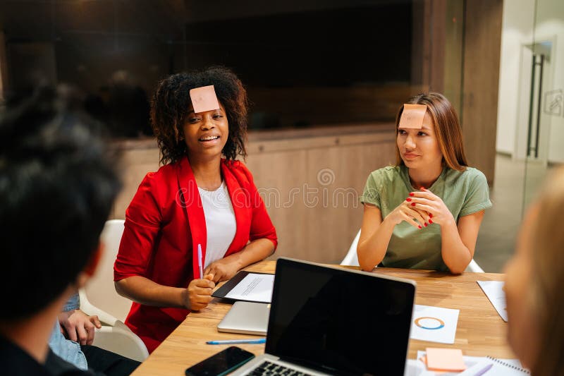 Diversi team di business felici che giocano a indovinare con note appiccicose sulla fronte dopo lavoro per intrattenimento. allegr immagine stock