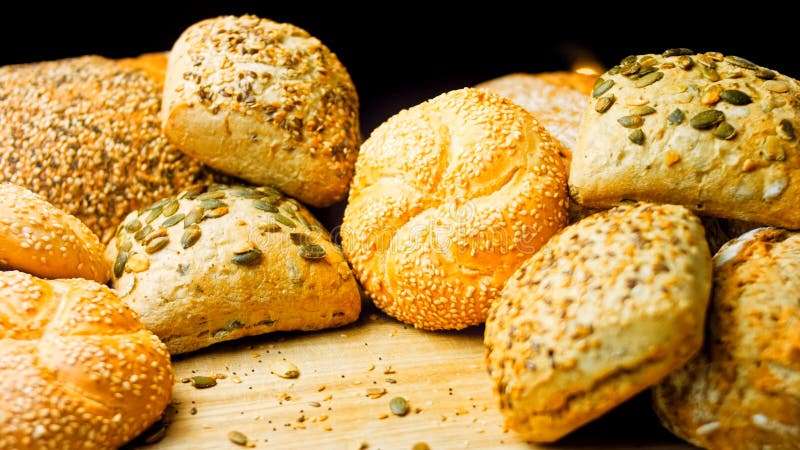 Diversi tipi di pane fresco sul tavolo di legno. assortimento isolato di pane su fondo bruno. ripresa con dispositivo di scorrimento.