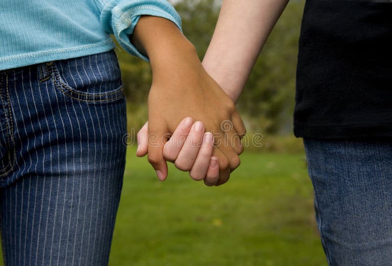 Image of girls holding hands, one white and one black, symbolizing unity. Image of girls holding hands, one white and one black, symbolizing unity