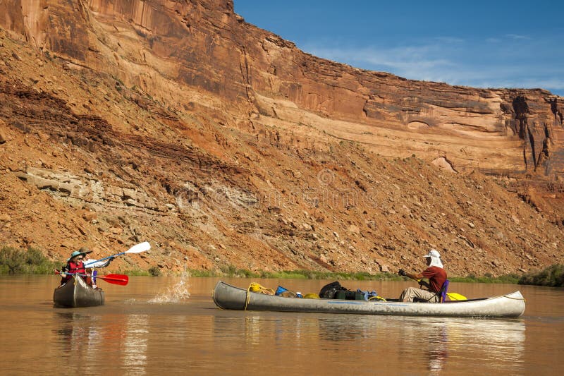 Diversión de la familia en el río del desierto en canoas