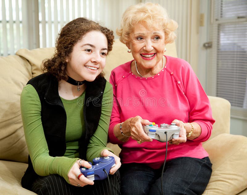 Teen girl has fun playing video games with her grandmother. Teen girl has fun playing video games with her grandmother.