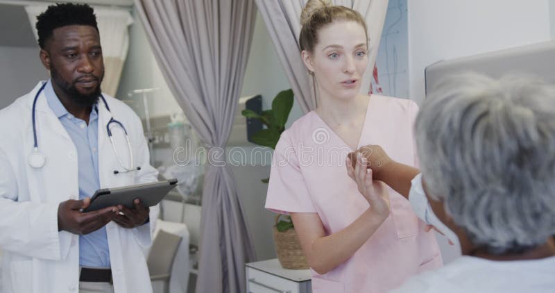 Diversos médicos masculinos con tablet y fisiología femenina feliz que tratan a pacientes de edad avanzada a cámara lenta almacen de metraje de vídeo