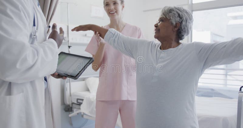 Diversos médicos masculinos con tablet y fisiología femenina feliz que tratan a pacientes de edad avanzada a cámara lenta almacen de metraje de vídeo