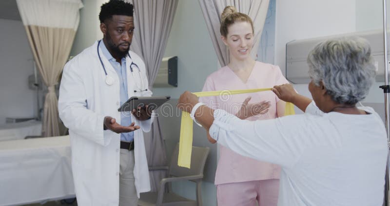 Diversos médicos masculinos hablan con fisioterapeutas femeninas felices y pacientes de edad avanzada a cámara lenta almacen de video