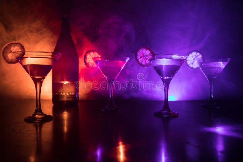 Several glasses of famous cocktail Martini, shot at a bar with dark toned foggy background and disco lights. Club drink concept. Selective focus. Several glasses of famous cocktail Martini, shot at a bar with dark toned foggy background and disco lights. Club drink concept. Selective focus