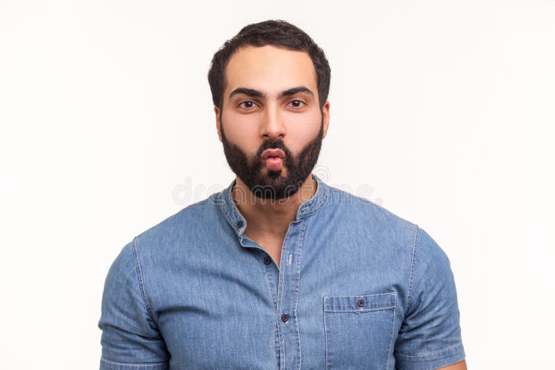 Funny comical man with beard in blue shirt folding lips pretending to be fish, making faces and having fun, good mood. Indoor studio shot isolated on white background. Funny comical man with beard in blue shirt folding lips pretending to be fish, making faces and having fun, good mood. Indoor studio shot isolated on white background