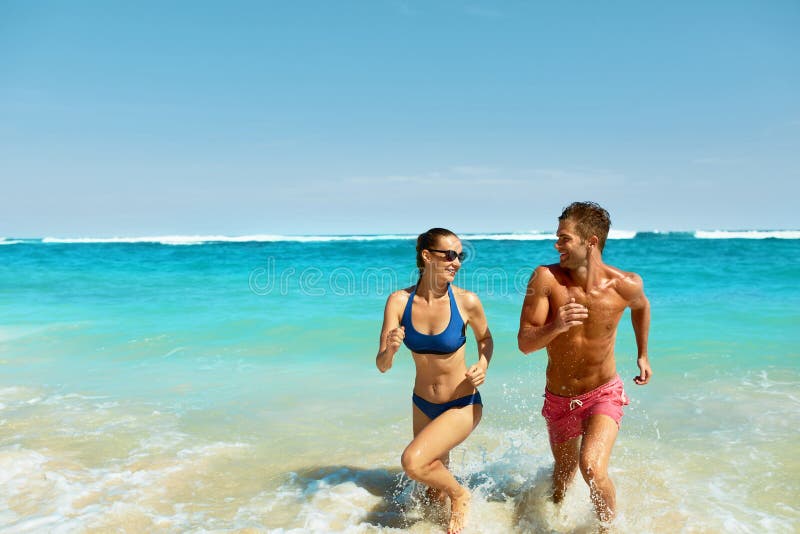 Divertimento delle coppie sulla spiaggia Gente romantica nel funzionamento di amore in mare immagini stock Divertimento delle coppie sulla spiaggia Gente romantica nel funzionamento di amore in mare immagini stock