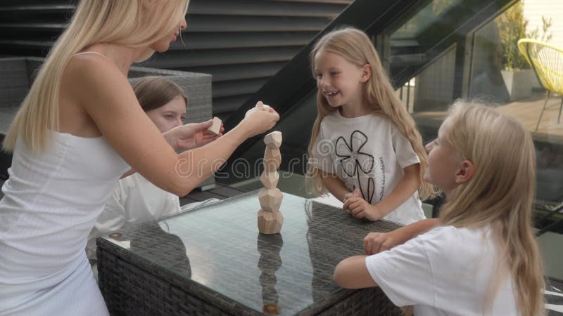 Divertimento familiare : Madre&figlie costruiscono e montano la torre di legno sul tetto video d archivio