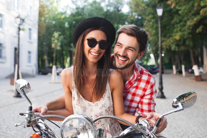 Divertiresi delle coppie dei pantaloni a vita bassa all'aperto sul motorino di estate immagine stock libera da diritti Divertiresi delle coppie dei pantaloni a vita bassa all'aperto sul motorino di estate immagine stock libera da diritti
