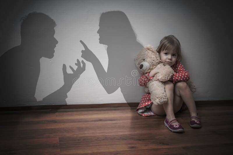 Divorce concept. Sad child is sitting at floor when parents argue.