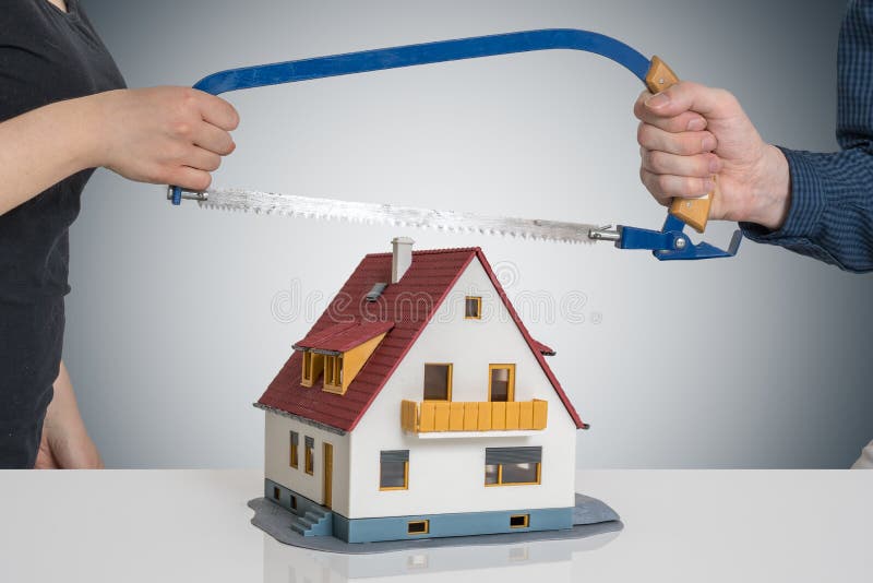 Divorzi e dividendo un concetto della casa L'uomo e la donna stanno spaccando il modello della casa con hanno visto immagine stock libera da diritti Divorzi e dividendo un concetto della casa L'uomo e la donna stanno spaccando il modello della casa con hanno visto immagine stock libera da diritti