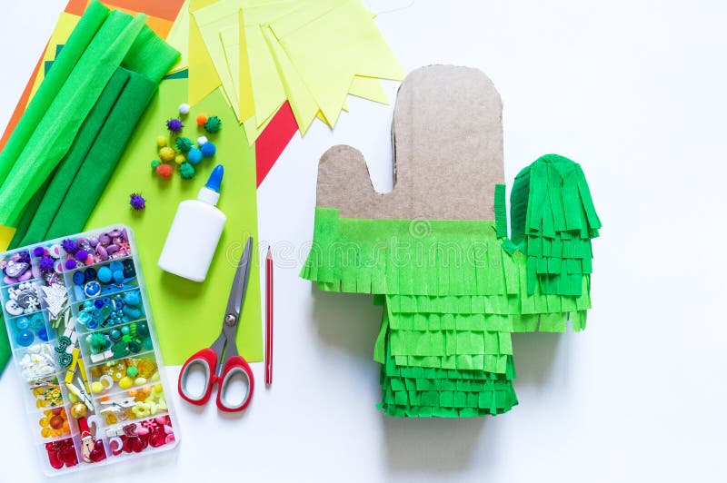 Diy cinco de mayo Mexican Pinata cactus made cardboard and crepe paper your own hands on a white background. Gift idea, decor, game cinco de mayo. Step by step. Top view. Process kid children craft