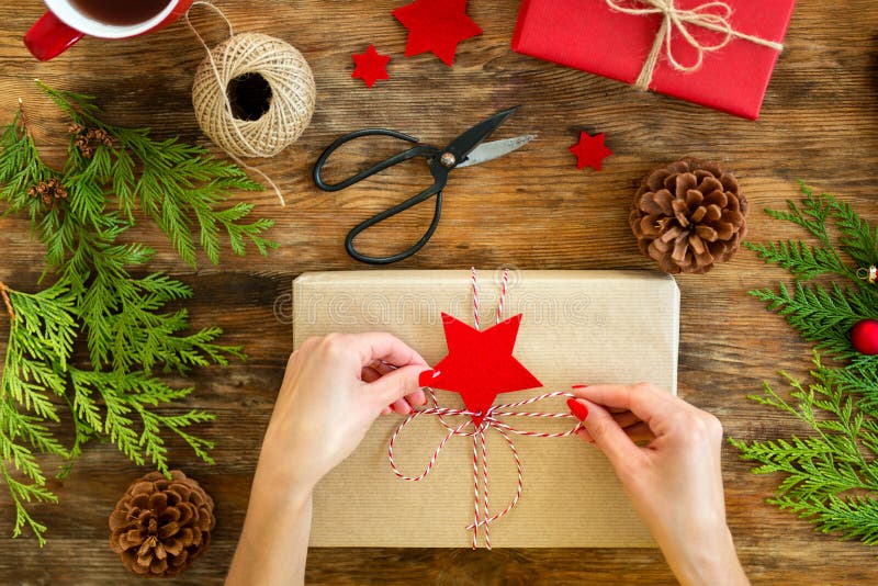 DIY-Geschenk-Verpackung Frau, die schöne rote Weihnachtsgeschenke auf rustikalem Holztisch einwickelt Obenliegende Ansichtweihnac