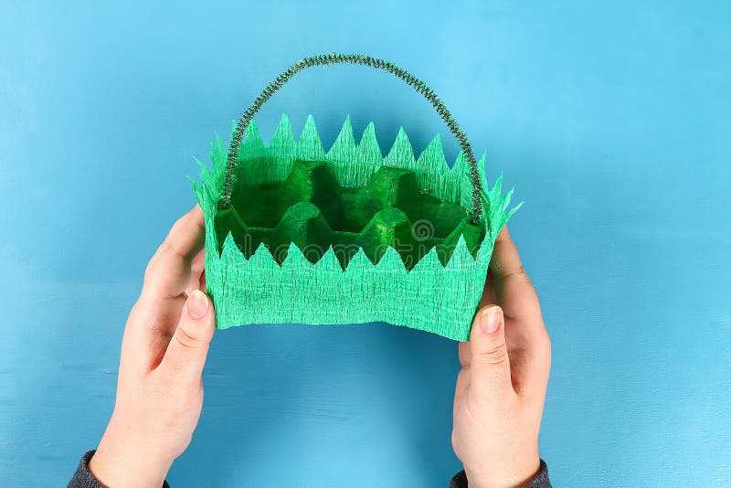 DIY-Korb Osterei vom Pappbehälter, Krepppapier, Chenillestamm auf blauem Hintergrund stockfoto DIY-Korb Osterei vom Pappbehälter, Krepppapier, Chenillestamm auf blauem Hintergrund stockfoto