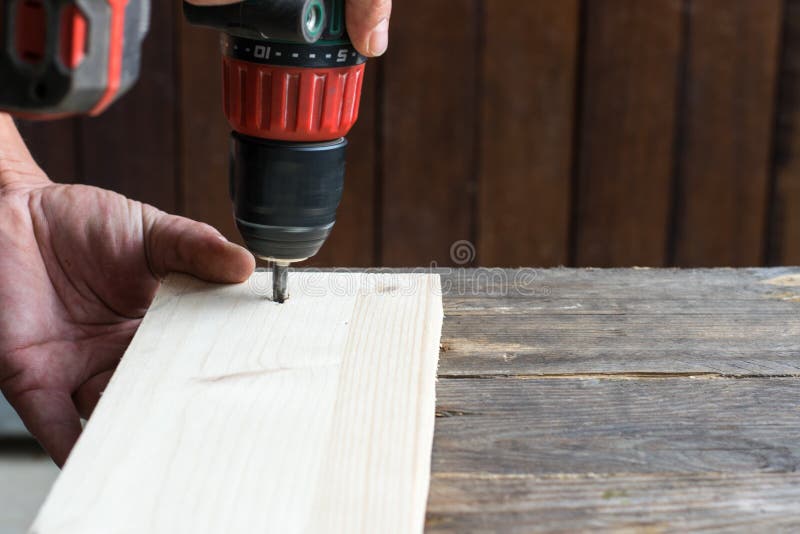 Diy - mano di un uomo facendo uso di un cacciavite su materiale di legno fotografia stock libera da diritti Diy - mano di un uomo facendo uso di un cacciavite su materiale di legno fotografia stock libera da diritti