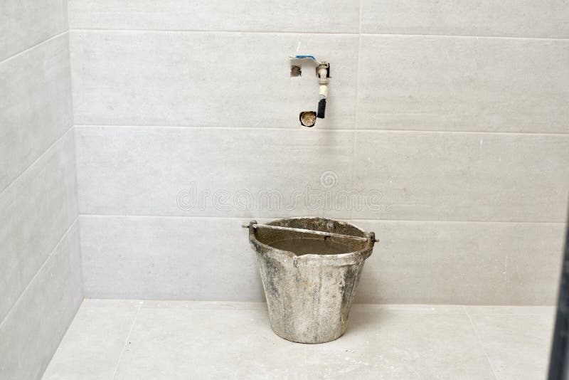 DIY, parede cerâmica da telha do tijolo em uma construção da sala das melhorias do banheiro Torneira e água enchida da cubeta imagens de stock royalty free DIY, parede cerâmica da telha do tijolo em uma construção da sala das melhorias do banheiro Torneira e água enchida da cubeta imagens de stock royalty free