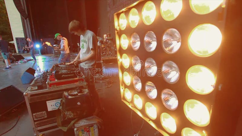 DJ, das am Sommerlivekonzert spinnt Musikband, die am Stadium durchführt Schlagzeuger, Gitarrist Spotlights