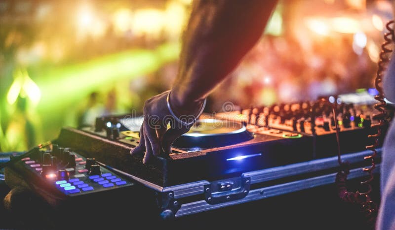 Dj mixing outdoor at beach party festival with crowd of people in background - Summer nightlife view of disco club outside - Soft